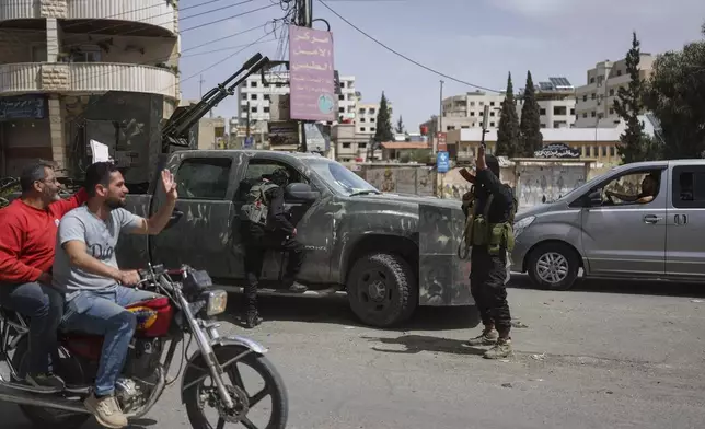 Syrian citizens salute members of Syria's security forces deployed in the town of Sahnaya, south of Damascus, Syria, Thursday, May 1, 2025, a day after clashes erupted between members of the minority Druze sect and pro-government fighters which left several people dead. (AP Photo/Ghaith Alsayed)