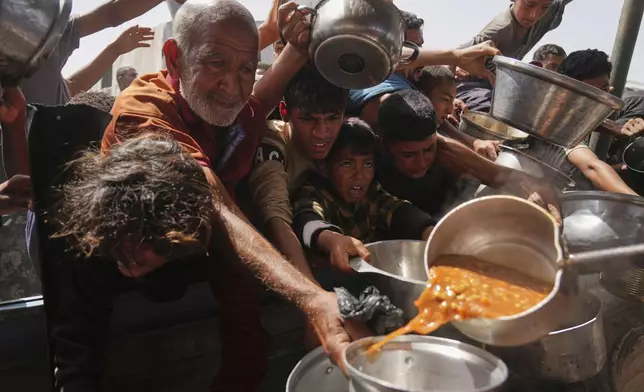 Palestinians struggle to get donated food at a community kitchen in Khan Younis, Gaza Strip, Sunday, May 11, 2025. (AP Photo/Abdel Kareem Hana)