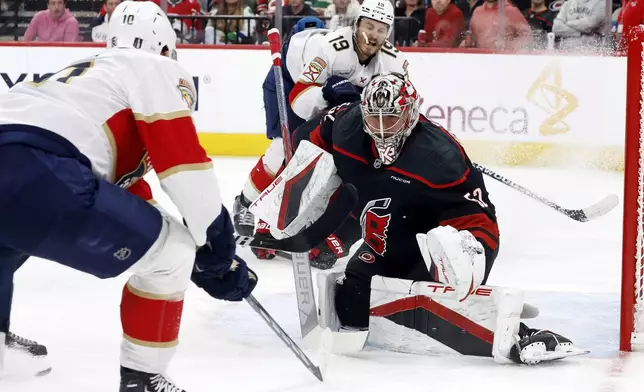 Carolina Hurricanes goaltender Pyotr Kochetkov (52) watches the puck from between Florida Panthers' A.J. Greer (10) an Matthew Tkachuk (19) during the third period of Game 2 of the NHL hockey Stanley Cup Eastern Conference finals in Raleigh, N.C., Thursday, May 22, 2025. (AP Photo/Karl DeBlaker)