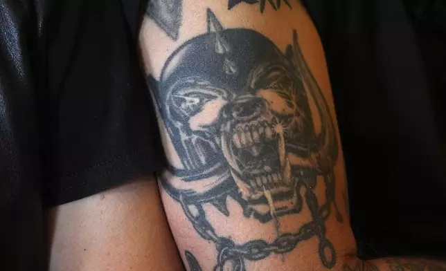 A tattoo of a Motorhead logo is seen on a man's arm as Motorhead fans gather to commemorate Lemmy Kilmister the Motorhead frontman in Burslem, Stoke on Trent, England, Friday, May 9, 2025. The musician, once described as having 'one of the most recognizable voices in rock', was born in Burslem and a statue has been crafted by acclaimed local sculptor and lifelong Motorhead fan Andy Edwards. (AP Photo/Kirsty Wigglesworth)
