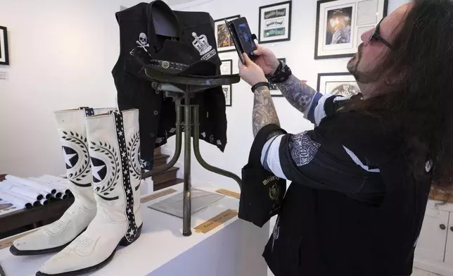 A man photographs items as Motorhead fans meet to commemorate Lemmy Kilmister the Motorhead frontman in Burslem, Stoke on Trent, England, Friday, May 9, 2025. The musician, once described as having 'one of the most recognizable voices in rock', was born in Burslem and a statue has been crafted by acclaimed local sculptor and lifelong Motorhead fan Andy Edwards. (AP Photo/Kirsty Wigglesworth)