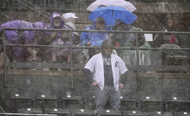 Fans are drenched as a heavy rain sweeps over Coors Field in the top of the fifth inning of a baseball game between the New York Yankees and the Colorado Rockies, Sunday, May 25, 2025, in Denver. (AP Photo/David Zalubowski)