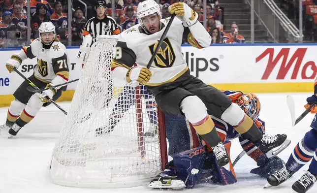 Vegas Golden Knights' Reilly Smith (19) falls over Edmonton Oilers goalie Stuart Skinner, center bottom, during the first period of Game 3 of a second-round NHL hockey playoff series in Edmonton, Alberta, Saturday, May 10, 2025. (Jason Franson/The Canadian Press via AP)