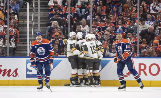 Vegas Golden Knights players, center, celebrate after a goal as Edmonton Oilers' Brett Kulak (27) and Darnell Nurse (25) skate past during the second period of Game 3 of a second-round NHL hockey playoff series in Edmonton, Alberta, Saturday, May 10, 2025. (Jason Franson/The Canadian Press via AP)