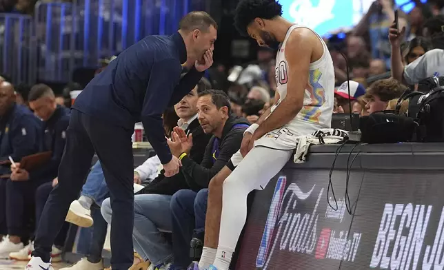 Denver Nuggets interim head coach David Adelman, left, confers with guard Jamal Murray as he sits on the scorer's table during a break in play in the first half of Game 6 in the Western Conference semifinals of the NBA basketball playoffs Thursday, May 15, 2025, in Denver. (AP Photo/David Zalubowski)