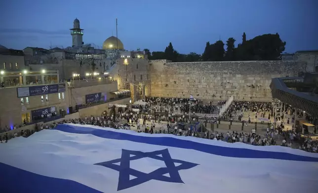 Members of Jewish youth movements unfurl a giant Israeli flag on the eve of Jerusalem Day an Israeli holiday celebrating the capture of the Old City during the 1967 Mideast war, next to the Western Wall in the Old City of Jerusalem, Sunday, May 25, 2025. (AP Photo/Ohad Zwigenberg)