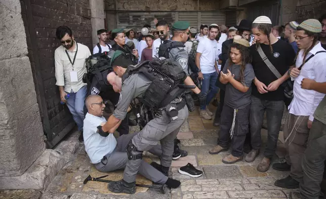 Israeli police officers assist a Palestinian man after he was pushed by Israelis as they mark Jerusalem Day, an Israeli holiday celebrating the capture of east Jerusalem in the 1967 Mideast war, in Jerusalem's Old City, Monday, May 26, 2025. (AP Photo/Ohad Zwigenberg)