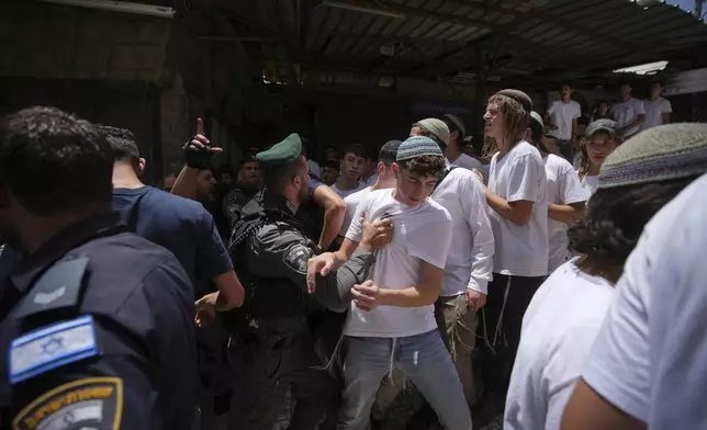 Israeli police scuffle with Israeli youths during a march marking Jerusalem Day, an Israeli holiday celebrating the capture of east Jerusalem in the 1967 Mideast war, in Jerusalem's Old City, Monday, May 26, 2025. (AP Photo/Ohad Zwigenberg)