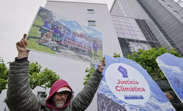 A protestor demands climate justice in front of the Higher Regional Court in Hamm, Germany, ahead of the verdict in the climate lawsuit brought by Peruvian farmer Luciano Lliuya against German energy company RWE, Wednesday, May 28, 2025. (AP Photo/Martin Meissner)