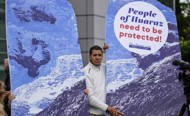 A protestor demands climate justice in front of the Higher Regional Court in Hamm, Germany, ahead of the verdict in the climate lawsuit brought by Peruvian farmer Luciano Lliuya against German energy company RWE, Wednesday, May 28, 2025. (AP Photo/Martin Meissner)
