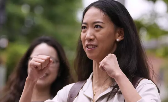 Yurong "Luanna" Jiang, who delivered a speech at her Harvard University commencement, raises her fists while talking with friends, Friday, May 30, 2025, in Cambridge, Mass. (AP Photo/Charles Krupa)