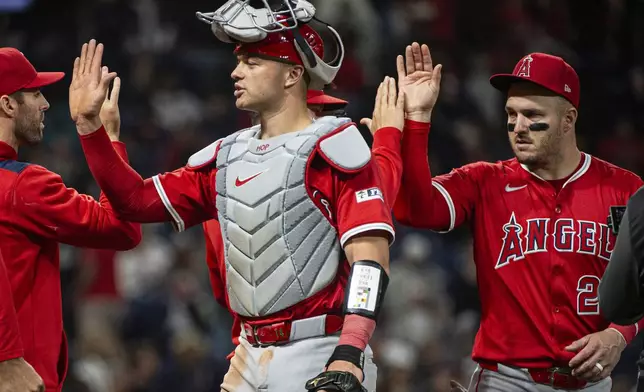 Los Angeles Angels' Logan O'Hoppe, left, and Mike Trout, right greet their teammates at the end of a baseball game against the Cleveland Guardians, Friday, May 30, 2025, in Cleveland. (AP Photo/Phil Long)