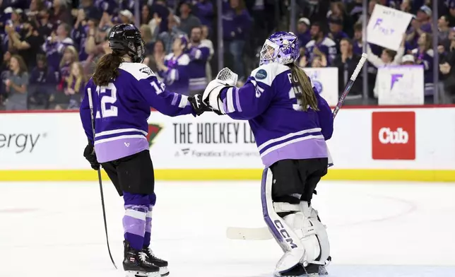Minnesota Frost forward Kelly Pannek (12) and goaltender Maddie Rooney, right, celebrate after Pannek's goal during the second period of Game 4 of the PWHL hockey finals against the Ottawa Charge, Monday, May 26, 2025, in St. Paul, Minn. (AP Photo/Ellen Schmidt)