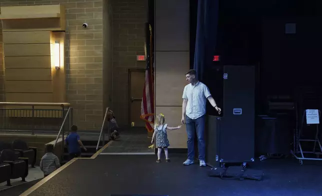 Jake Rogers, a pastor and former member of the U.S. Marine Corps, and his daughter help clean up the stage after church on Sunday, April 6, 2025, at Pillar Church in Dumfries, Va. (AP Photo/Jessie Wardarski)