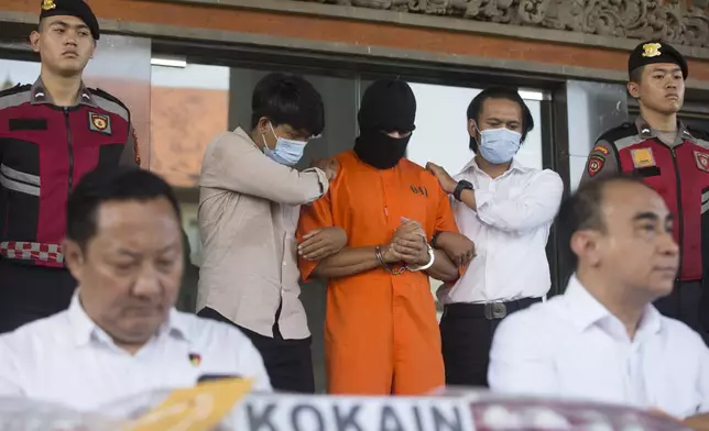 An Australian man arrested for allegedly smuggling cocaine stands after escorted to a news conference at the police headquarters in Bali, Indonesia, Monday, May 26, 2025. (AP Photo/Firdia Lisnawati)