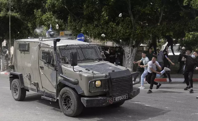 Palestinians throw stones at an Israeli security forces vehicle during clashes that erupted following an army raid in the West Bank city of Nablus on Sunday, May 4, 2025. (AP Photo/Majdi Mohammed)
