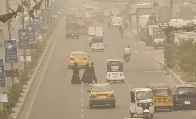 Iraqis walk through the streets during a heavy sandstorm in Baghdad, Iraq, Sunday, May 4, 2025. (AP Photo/Hadi Mizban)