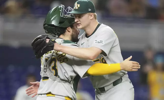 Oakland Athletics catcher Shea Langeliers (23) and relief pitcher Noah Murdock, right, embrace after defeating the Miami Marlins in a baseball game, Friday, May 2, 2025, in Miami. (AP Photo/Lynne Sladky)