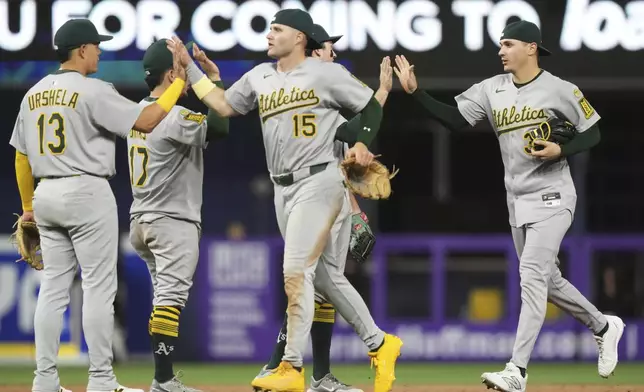 Oakland Athletics third baseman Gio Urshela (13), right fielder Seth Brown (15) and center fielder JJ Bleday, right, high five after defeating the Miami Marlins in a baseball game, Friday, May 2, 2025, in Miami. (AP Photo/Lynne Sladky)