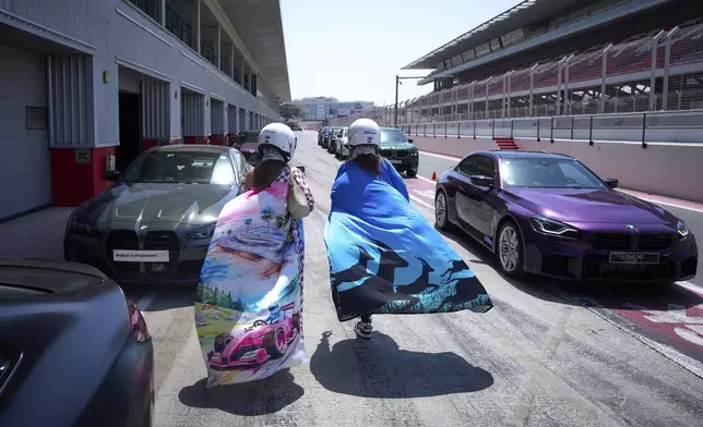 Drivers walk between supercars before the start of the first all-women rally in Dubai, United Arab Emirates, Thursday, May 1, 2025. (AP Photo/ Fatima Shbair)