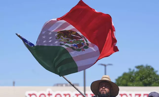 A float rider waves a U.S.-Mexico flag during a Cinco de Mayo parade in the Oak Cliff section of Dallas, Saturday, May 3, 2025. (AP Photo/LM Otero)