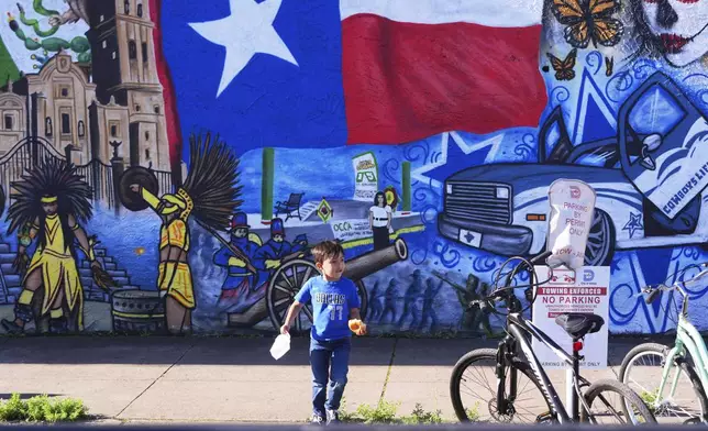 Luca Fernandez, 5, walks in front of a mural made by artist Jesus Alba to commemorate the 1862 battle of Puebla between the French and Mexican army during a Cinco De Mayo celebration in the Oak Cliff section of Dallas, May 3, 2025. (AP Photo/LM Otero)