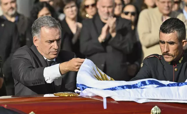 Uruguayan President Yamandu Orsi covers the casket of the late, former Uruguayan President Jose Mujica with the national flag at the presidential palace in Montevideo, Uruguay, Wednesday, May 14, 2025. (AP Photo/Santiago Mazzarovich)