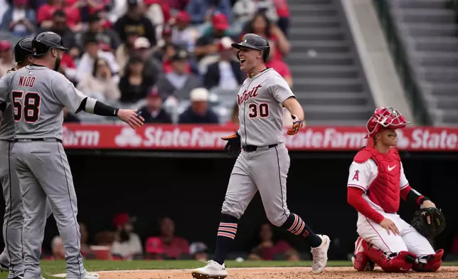 Detroit Tigers' Kerry Carpenter, center, is congratulated by Javier Báez, left, and Tomás Nido after hitting a three-run home run as Los Angeles Angels catcher Logan O'Hoppe kneels at the plate during the sixth inning of a baseball game Sunday, May 4, 2025, in Anaheim, Calif. (AP Photo/Mark J. Terrill)