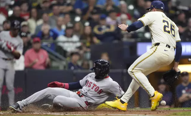 Boston Red Sox's Ceddanne Rafaela, left, scores from third base on a wild pitch past Milwaukee Brewers' Aaron Ashby, right, during the sixth inning of a baseball game Tuesday, May 27, 2025, in Milwaukee. (AP Photo/Aaron Gash)