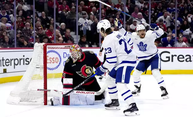 Toronto Maple Leafs' William Nylander, right, and Matthew Knies (23) celebrate as Auston Matthews (not shown) scores against Ottawa Senators goaltender Linus Ullmark (35) during the first period of Game 6 of a first-round NHL hockey playoff series in Ottawa, Ontario, Thursday, May 1, 2025. (Justin Tang/The Canadian Press via AP)