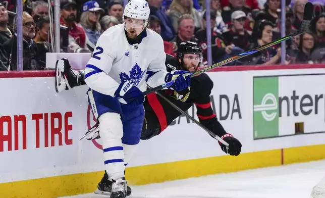 Ottawa Senators' Michael Amadio, right, is knocked off his skates after a hit into the boards by Toronto Maple Leafs' Simon Benoit (2) during the second period of Game 6 of a first-round NHL hockey playoff series in Ottawa, Ontario, Thursday, May 1, 2025. (Justin Tang/The Canadian Press via AP)