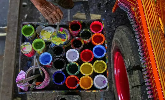An artisan mixes colors as he paints art on a truck at a yard for workshops in Rawalpindi, Pakistan, on Saturday, April 19, 2025. (AP Photo/Anjum Naveed)