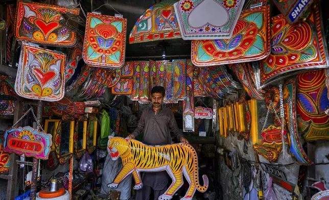 A vendor displays metal pieces painted in the style of traditional art used to decorate trucks at a shop in Rawalpindi, Pakistan, on Saturday, April 19, 2025. (AP Photo/Anjum Naveed)