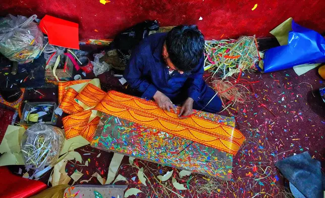 An artisan makes traditional patterns with colorful stickers used to decorate trucks at a yard for workshops in Rawalpindi, Pakistan, on Saturday, April 19, 2025. (AP Photo/Anjum Naveed)