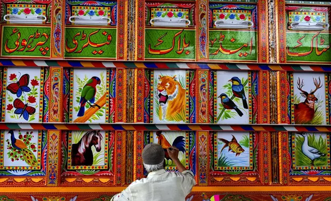 An artisan paints art on a truck at a yard for workshops in Rawalpindi, Pakistan, on Saturday, April 19, 2025. (AP Photo/Anjum Naveed)