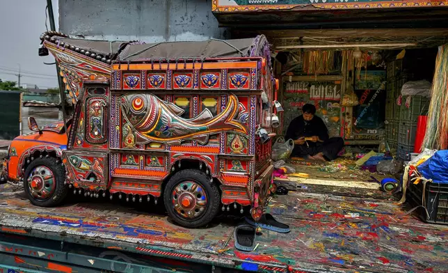 An artisan makes traditional patterns with colorful stickers used to decorate trucks at a yard for workshops in Rawalpindi, Pakistan, on Saturday, April 19, 2025. (AP Photo/Anjum Naveed)