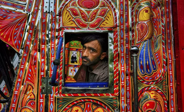 Driver Farrukh Sana looks out from the window of a newly refurbished truck at a yard for workshops in Rawalpindi, Pakistan, on Saturday, April 19, 2025. (AP Photo/Anjum Naveed)