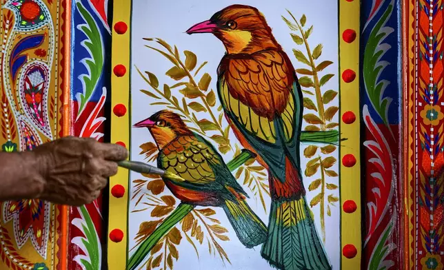 An artisan paints birds on a truck at a yard for workshops in Rawalpindi, Pakistan, on Saturday, April 19, 2025. (AP Photo/Anjum Naveed)