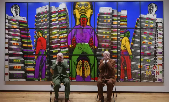 Artists Gilbert &amp; George pose with artwork at their exhibition called 'DEATH HOPE LIFE FEAR…' an exhibition of 18 pictures by Gilbert &amp; George that span the years 1984 to 1998, at the Gilbert &amp; George Centre in London, Wednesday, May 14, 2025. (AP Photo/Kirsty Wigglesworth)