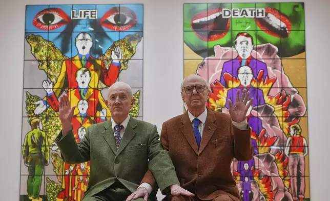 Art duo Gilbert &amp; George pose with artwork at their exhibition called 'DEATH HOPE LIFE FEAR…' an exhibition of 18 pictures by Gilbert &amp; George that span the years 1984 to 1998, at the Gilbert &amp; George Centre in London, Wednesday, May 14, 2025. (AP Photo/Kirsty Wigglesworth)