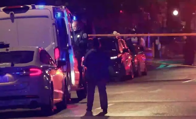 In this image taken from video provided by WJLA, a spectator watches as law enforcement works the scene after two staff members of the Israeli embassy in Washington were shot and killed outside the Capital Jewish Museum on Wednesday, May 21, 2025, in Washington. (WJLA via AP)