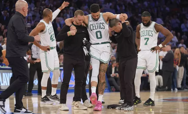 Trainers help Boston Celtics' Jayson Tatum (0) off the court after he was injured during the second half of Game 4 in the Eastern Conference semifinals of the NBA basketball playoffs against the New York Knicks Monday, May 12, 2025, in New York. (AP Photo/Frank Franklin II)
