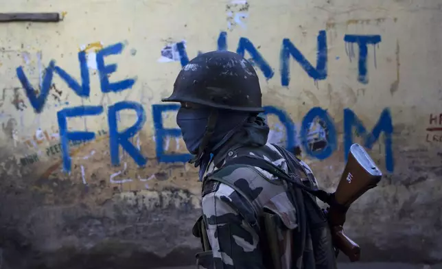 FILE - An Indian paramilitary soldier walks past graffiti on a wall in Srinagar, Indian-controlled Kashmir, Aug. 29, 2016. (AP Photo/Dar Yasin, File)