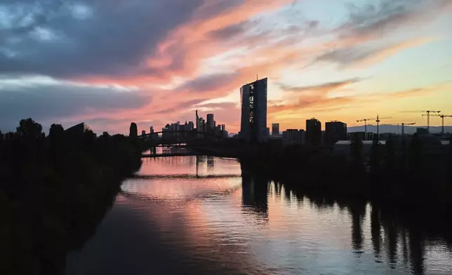 The sun sets behind the European Central Bank building, foreground center, in Frankfurt, Germany, Saturday, April 26, 2025. (AP Photo/Michael Probst)