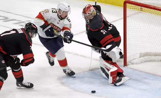Florida Panthers center Brad Marchand (63) drives against Carolina Hurricanes defenseman Alexander Nikishin (21) and goaltender Frederik Andersen (31) during the first Period in Game 5 of the NHL hockey Stanley Cup Eastern Conference finals Wednesday, May 28, 2025, in Raleigh, N.C. (AP Photo/Chris Seward)