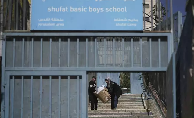 A student and a teacher carry study material at UNRWA Girls School run by the U.N. agency for Palestinian refugees in the Shuafat Refugee Camp in east Jerusalem, Thursday, May 8, 2025. After Israeli forces ordered the closure of six of its schools in east Jerusalem Thursday. (AP Photo/Mahmoud Illean)