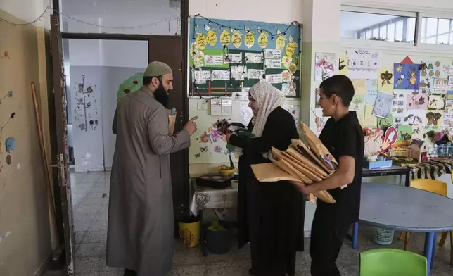 A student and a teacher carry study material at UNRWA School run by the U.N. agency for Palestinian refugees in the Shuafat Refugee Camp in east Jerusalem, Thursday, May 8, 2025. After Israeli forces ordered the closure of six of its schools in east Jerusalem Thursday. (AP Photo/Mahmoud Illean)