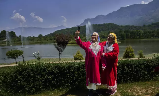 Surekha Dube, left, and Sunita Kamble, tourists from the Indian state of Maharashtra, take a selfie inside a deserted garden in Srinagar, Indian controlled Kashmir, India, Tuesday, May 20, 2025. (AP Photo/Dar Yasin)