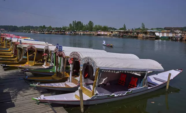 A Kashmiri flower vendor rows past anchored Shikaras, or traditional wooden boats, on Dal Lake in Srinagar, Indian controlled Kashmir, India, Tuesday, May 20, 2025. (AP Photo/Dar Yasin)