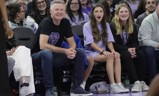 Golden State Warriors head coach Steve Kerr, foreground left, smiles during the second half of a WNBA basketball game between the Golden State Valkyries and the Los Angeles Sparks in San Francisco, Friday, May 16, 2025. (AP Photo/Jeff Chiu)